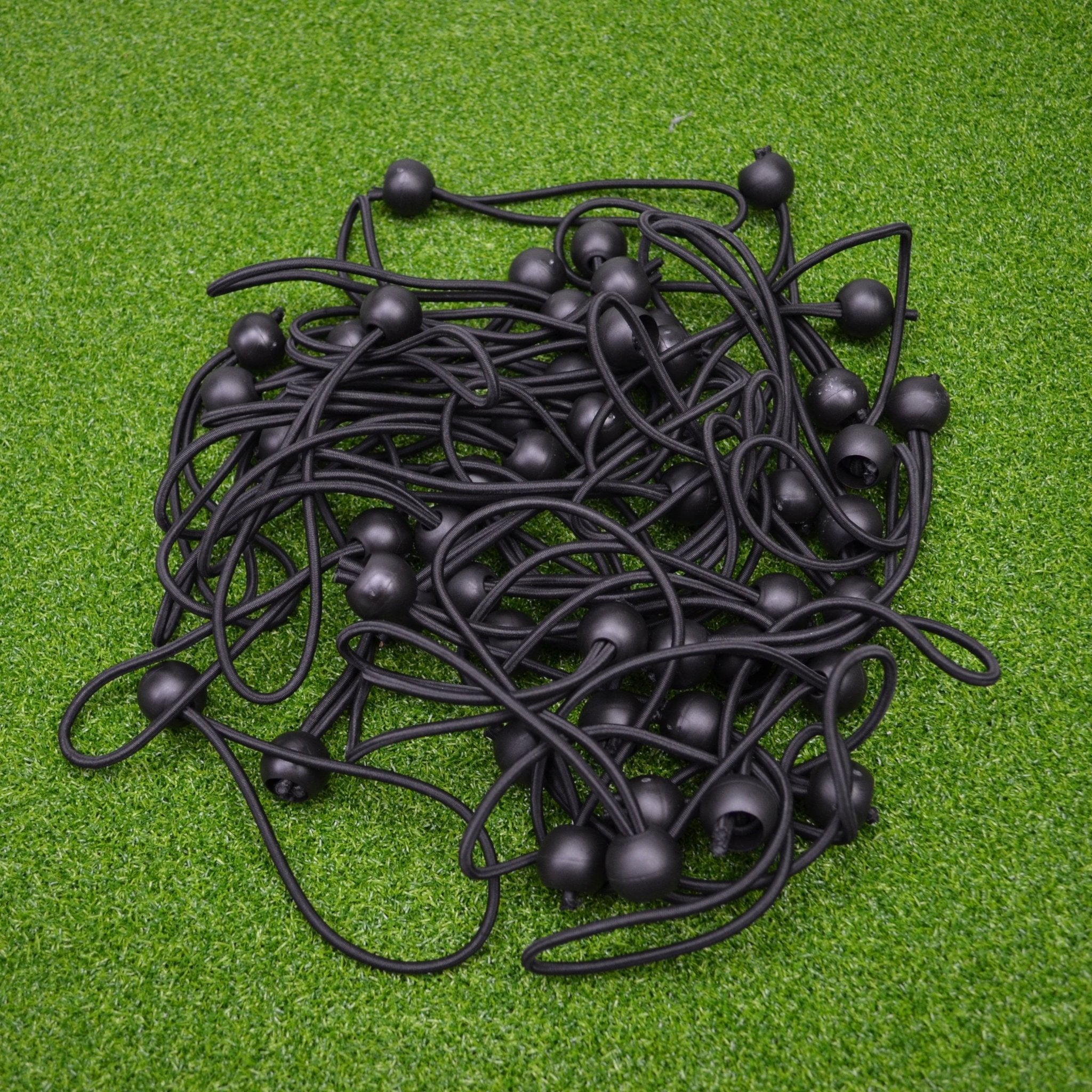 Collection of black ball bungies balls on a green surface