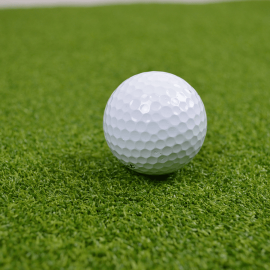 White golf ball on a green golf hitting mat