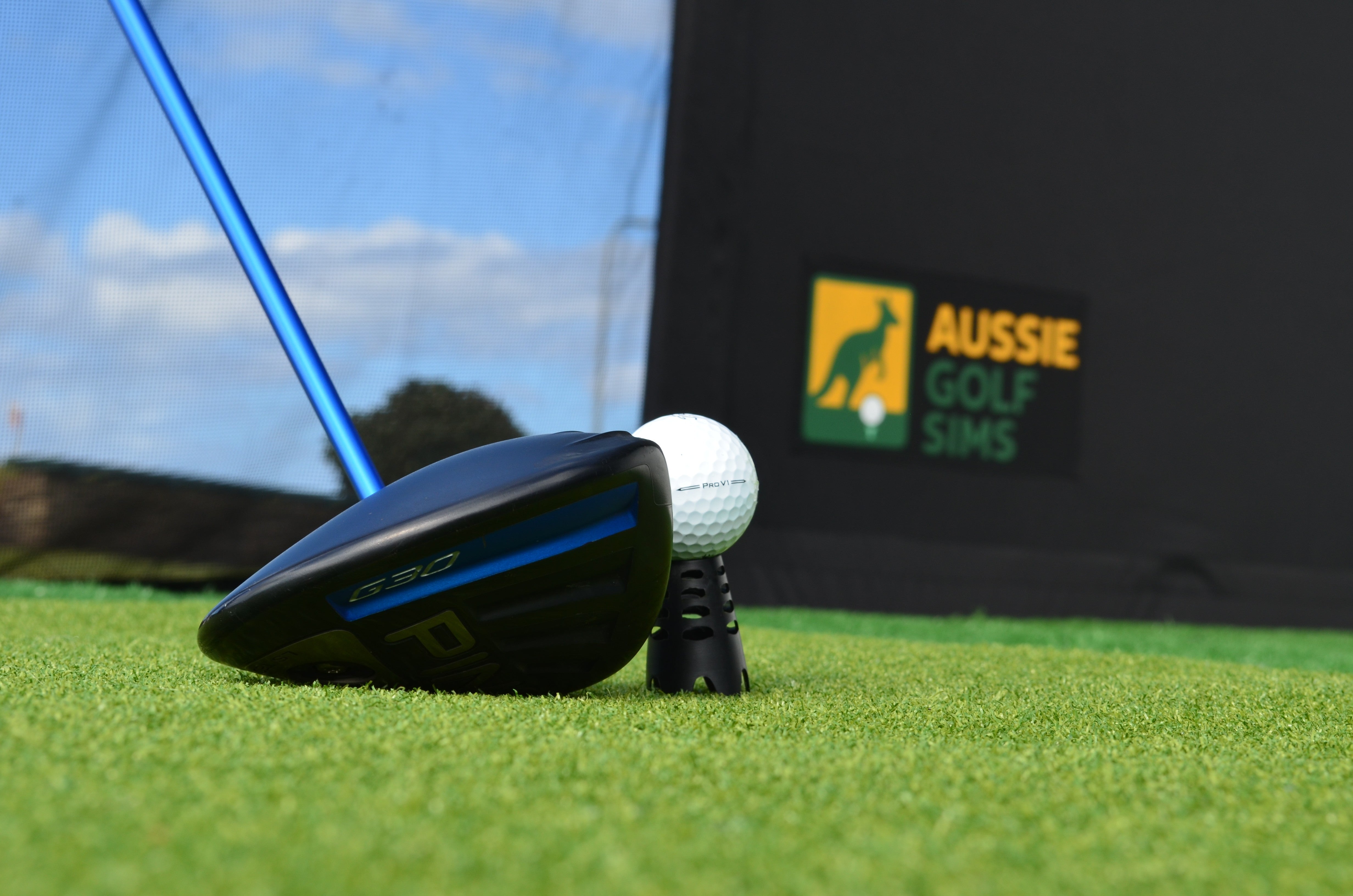 Golf club head and ball on a green surface with 'Aussie Golf Sims' branding in the background.