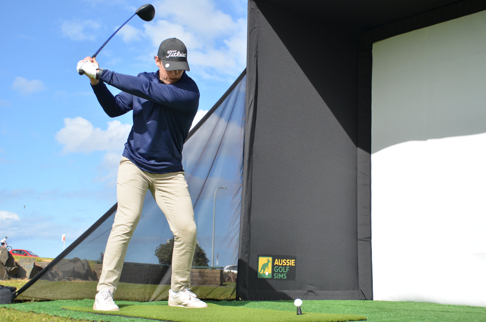 Man hitting golf ball into golf simulator enclosure