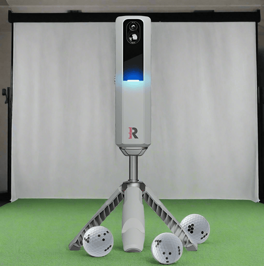 Rapsodo MLM2Pro with three golf balls on a green floor against a white curtain background