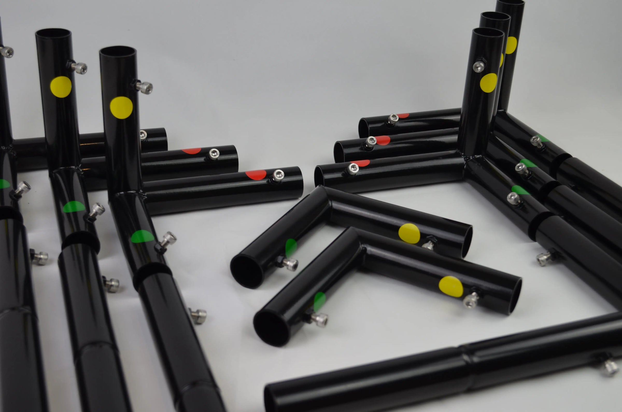 Black metal tubing with colorful yellow, red, and green dots, forming modular connections.