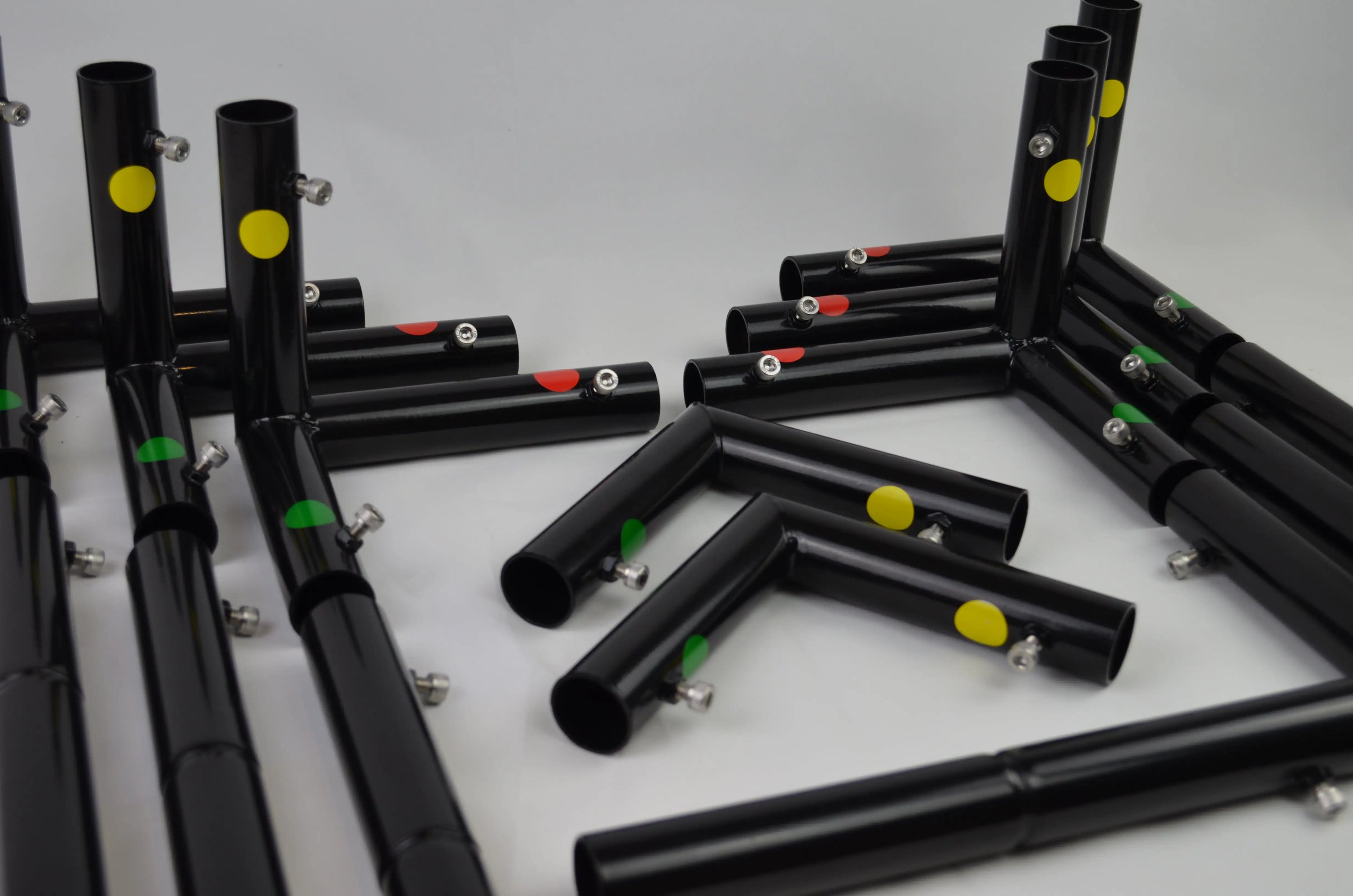 Black metal tubing with colorful yellow, red, and green dots, forming modular connections.