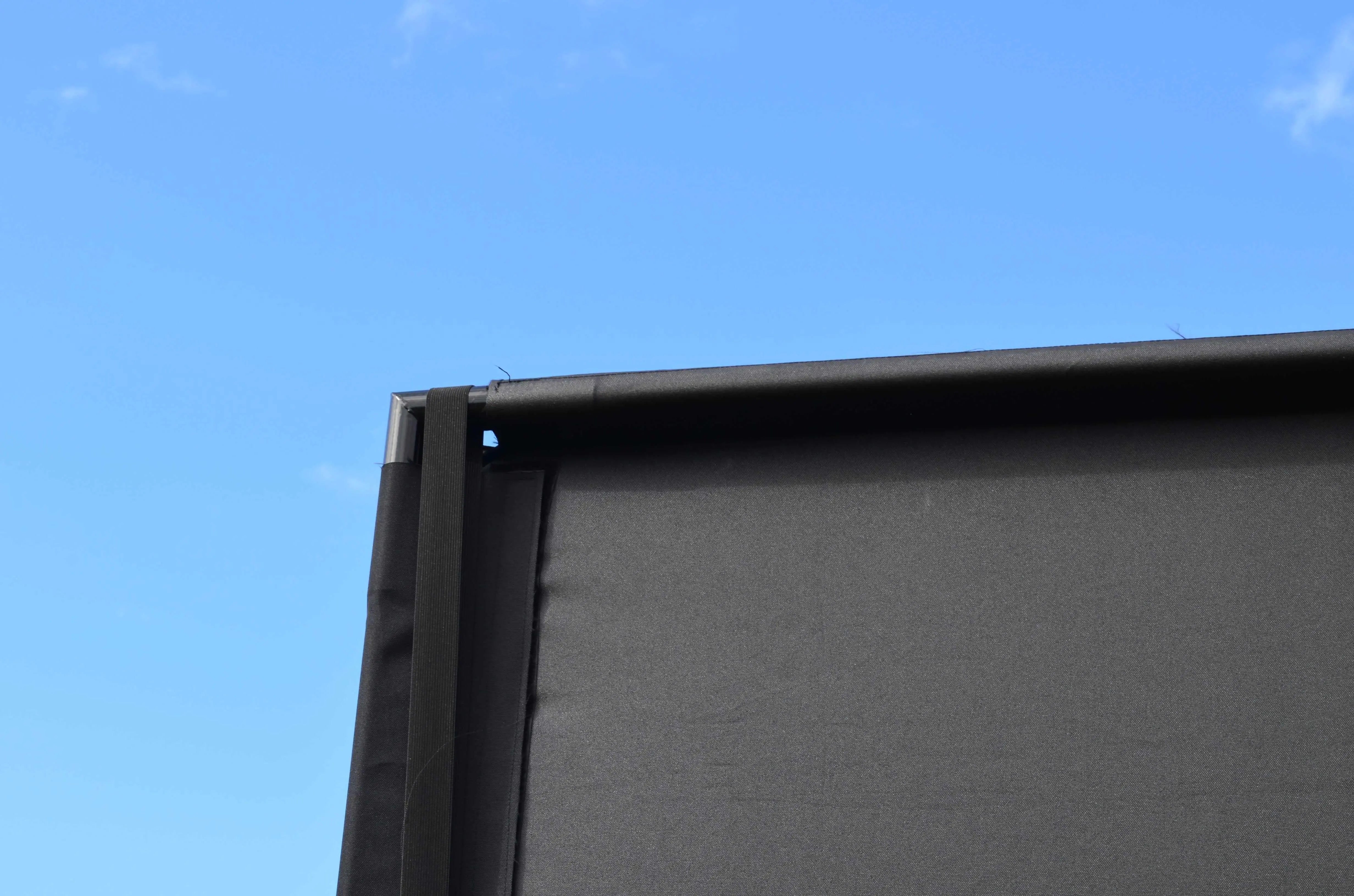 Corner of a golf simulator enclosure gainst a blue sk