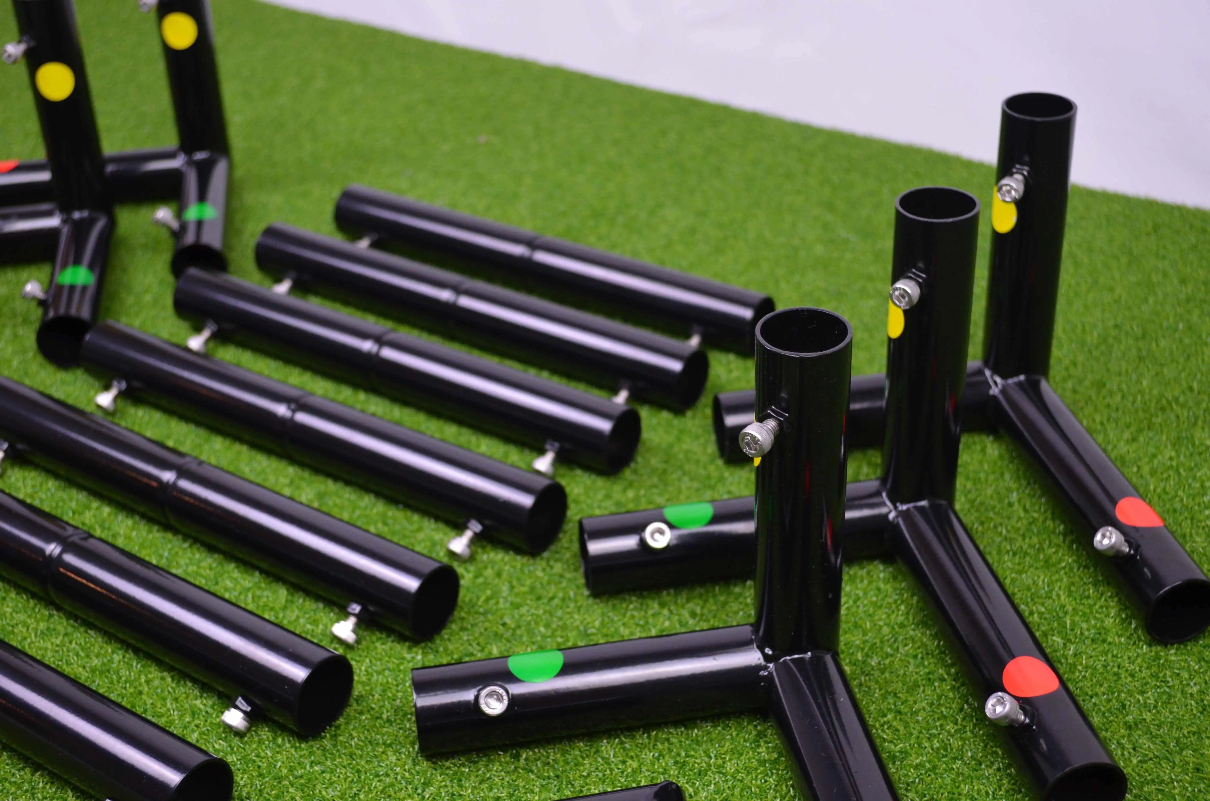 Black golf simulator enclosure corner peices with colorful markers on a green hitting mat