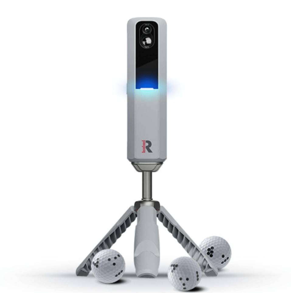 Rapsodo MLM2Pro golf launch monitor, light gray with blue light, on a tripod, with three Callaway RPT golf balls.