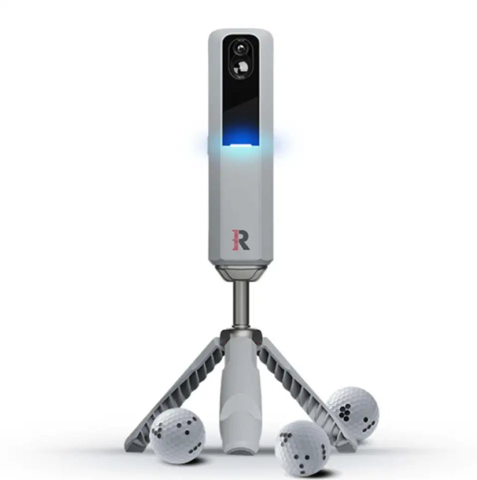 Rapsodo MLM2Pro golf launch monitor, light gray with blue light, on a tripod, with three Callaway RPT golf balls.