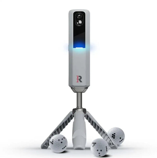 Rapsodo MLM2Pro golf launch monitor, light gray with blue light, on a tripod, with three Callaway RPT golf balls.