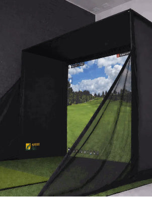 Golf simulator with screen displaying a golf course, surrounded by dark curtains.