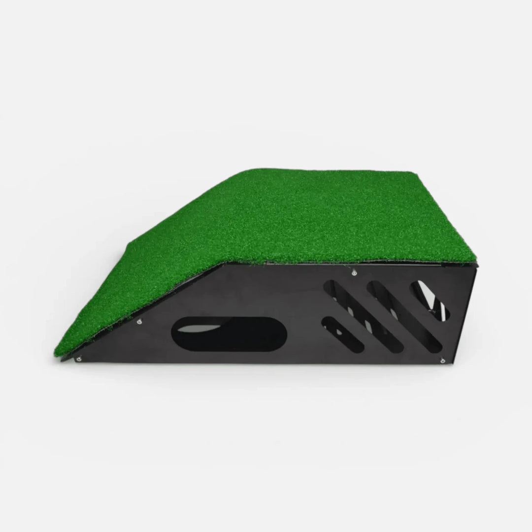 Black metal floor-mounted projector cover with green turf layer on top and clear front shield for golf simulator