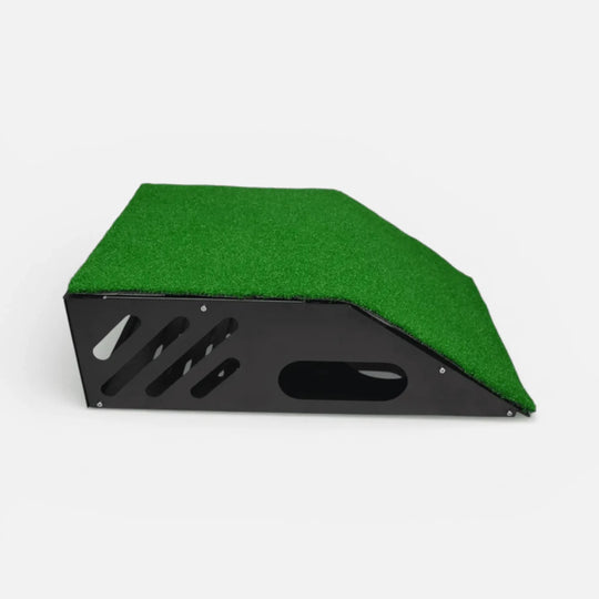 Black metal floor-mounted projector cover with green turf layer on top and clear front shield for golf simulator