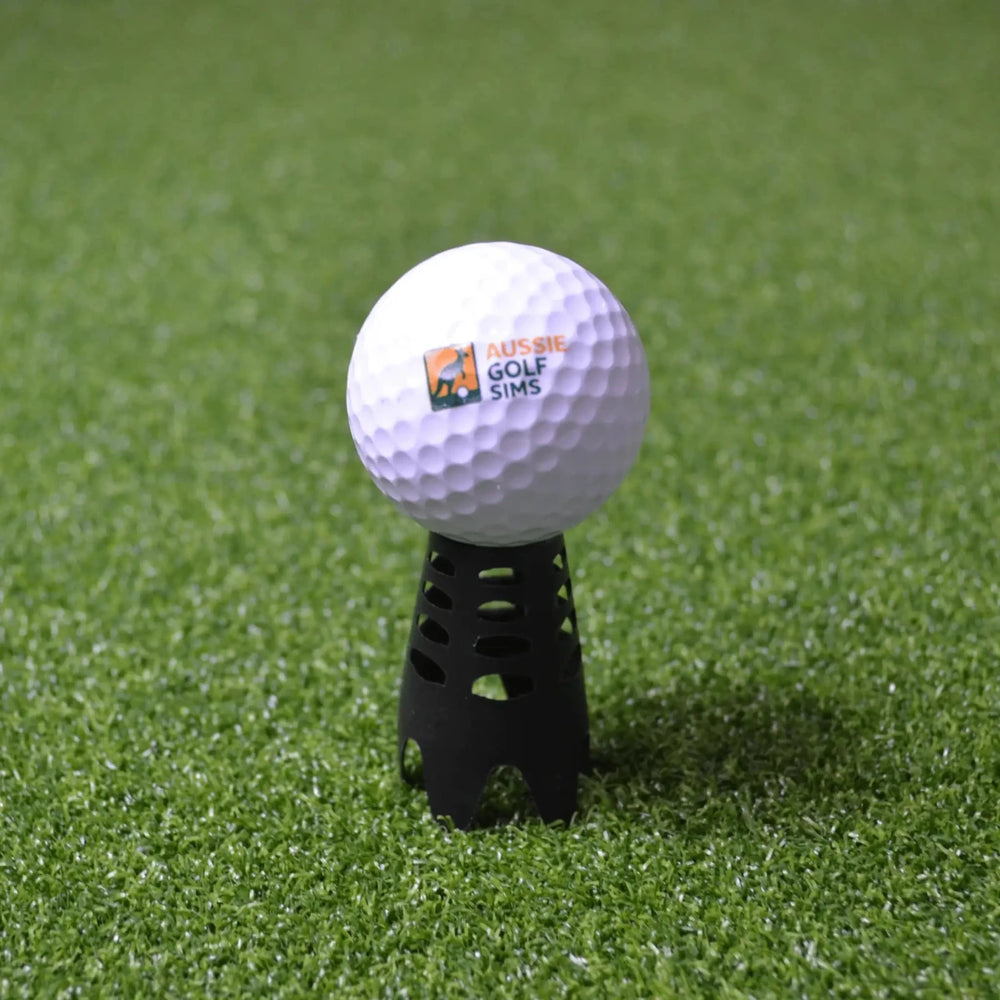 Black indoor golf tee sitting on green golf simulator turf with an "Aussie Golf Sims" branded ball set up on it