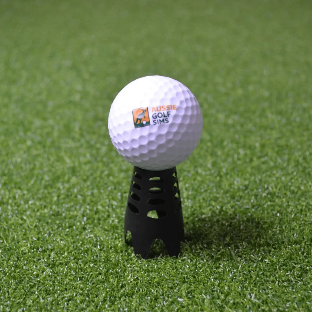 Black indoor golf tee sitting on green golf simulator turf with an "Aussie Golf Sims" branded ball set up on it