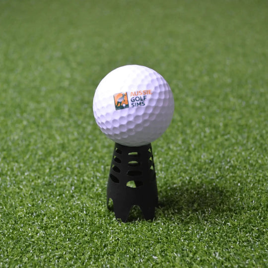 Black indoor golf tee sitting on green golf simulator turf with an "Aussie Golf Sims" branded ball set up on it