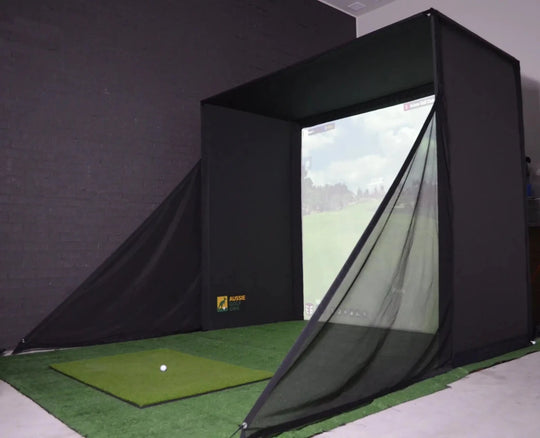 RooBox with side netting, hitting mat, in a room with a black wall, projecting an image of a golf course on the impact screen.
